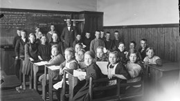 Svartvit bild från gammal skola föreställande lärare och barn.