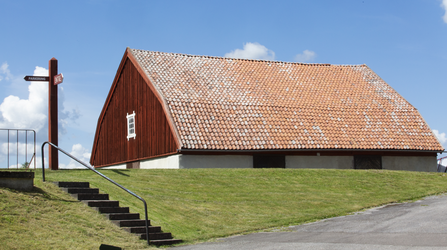Rött och vitt hus med tegeltak mot blå himmel.